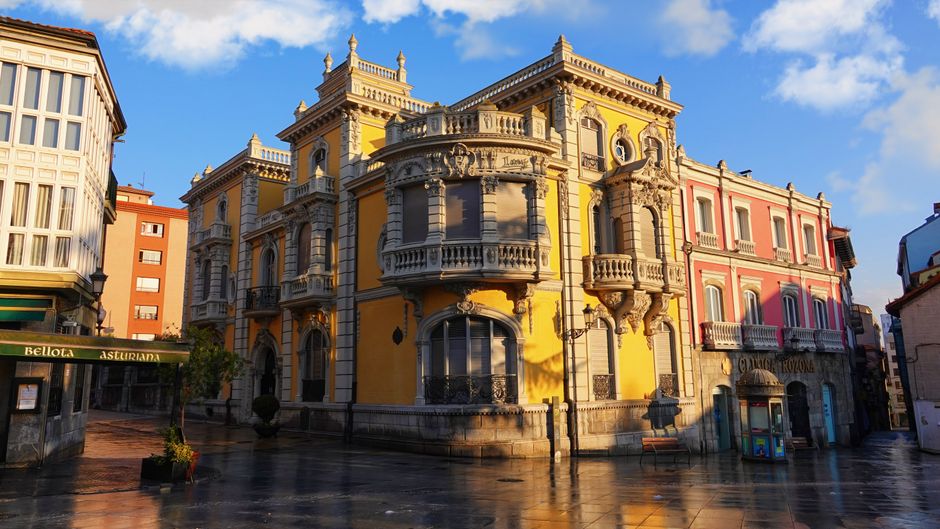 Edificio indiano de fachada amarilla en una plaza asturiana, tras la lluvia