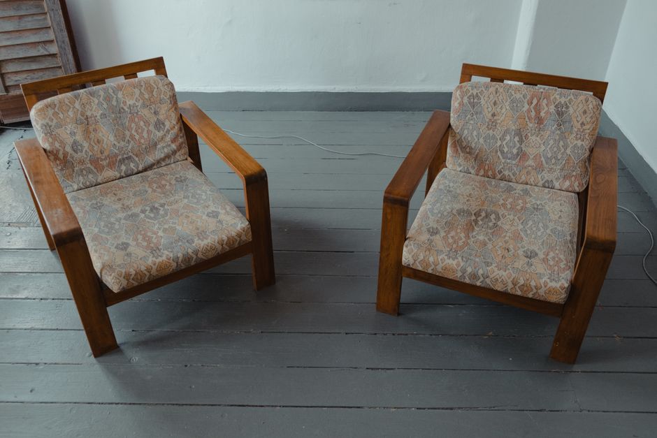 Dos butacas de madera enfrentadas en una habitación vacía, imagen de la sala de cornudos y parejas liberales