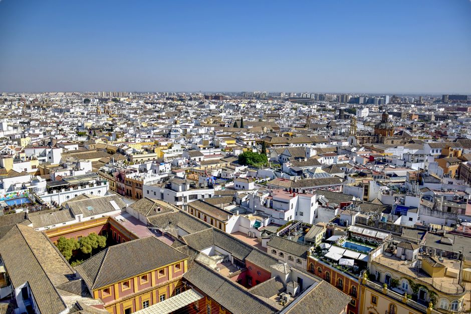 Los tejados del casco antiguo de Sevilla vistos desde arriba, con la ciudad extendiéndose hasta el horizonte bajo un cielo despejado.