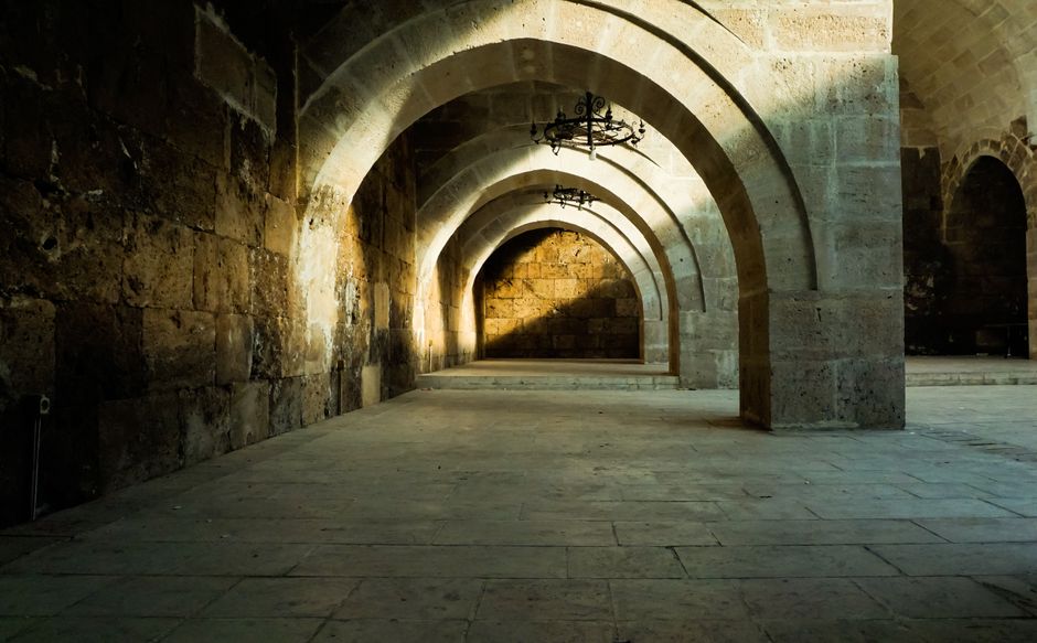 Arcos de piedra iluminados en penumbra, imagen del directorio de salas de Mazmorra