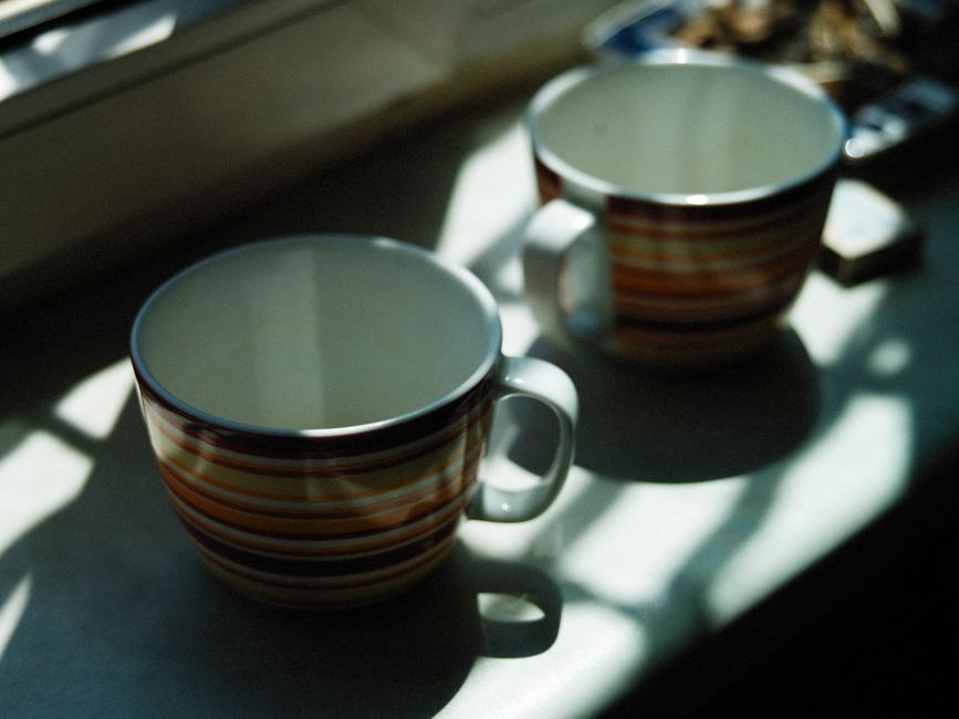 Dos tazas de rayas al sol en el alféizar de una cocina