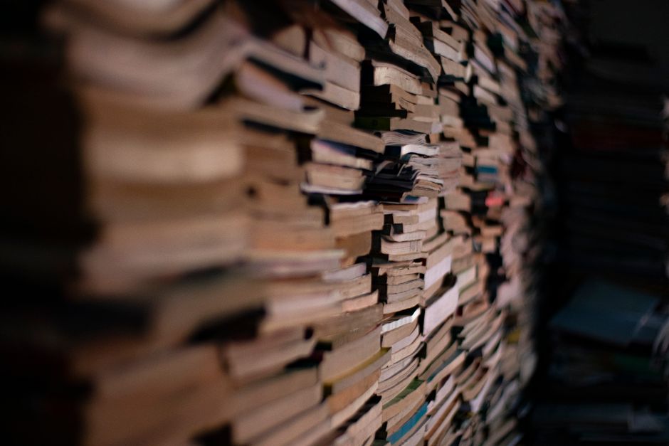 Montón de libros de bolsillo apilados en una habitación con poca luz