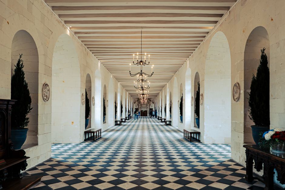 Galería simétrica de un castillo francés, con sus lámparas encendidas en fuga