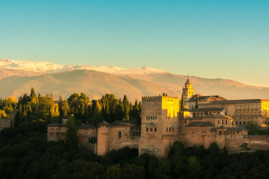 Chat BDSM de Granada: La Alhambra entre arboledas, con Sierra Nevada al fondo al atardecer