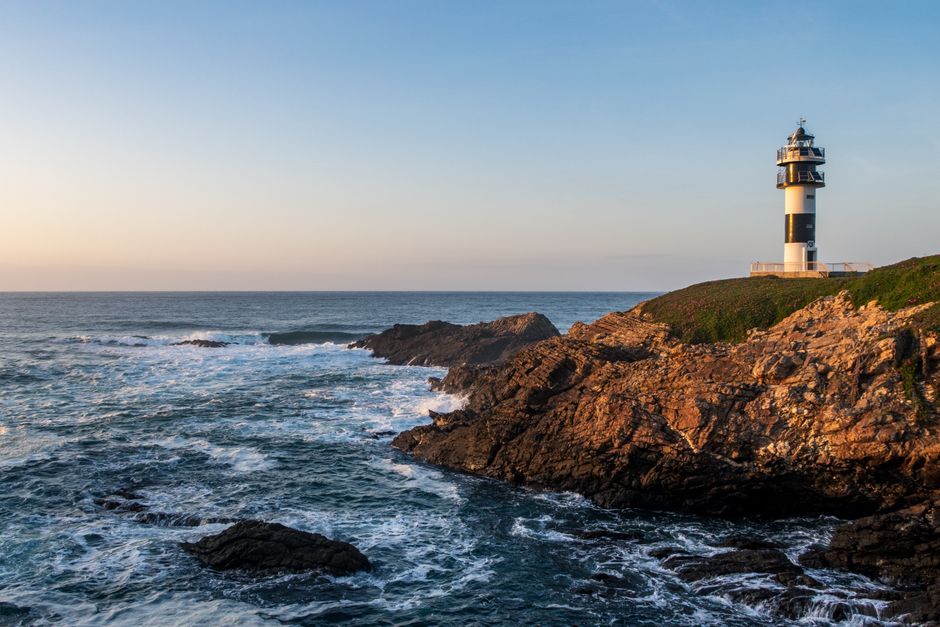 Galicia: Pancha Lighthouse against a stunning sea at dusk on the rugged coast of Spain.