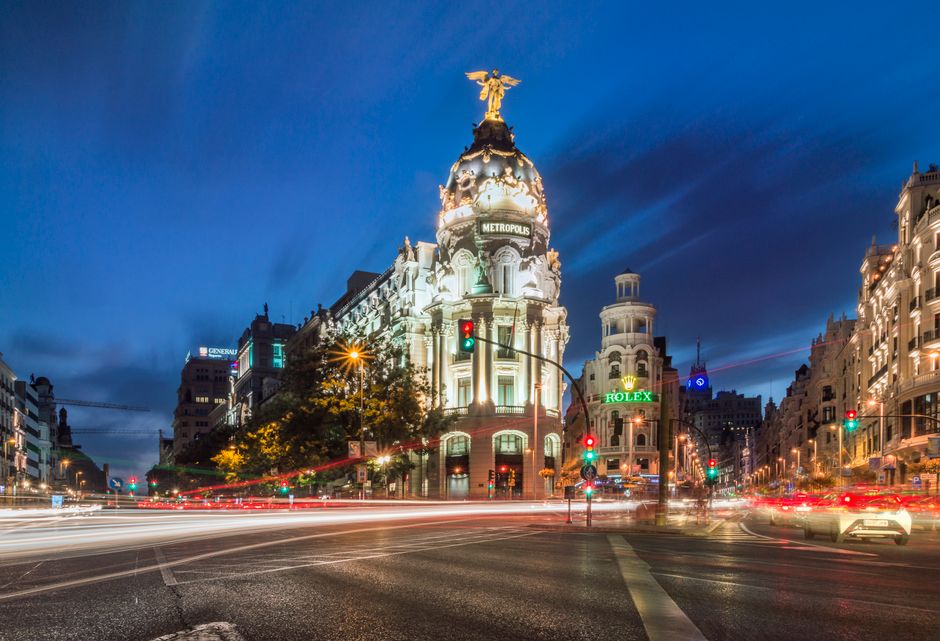 Madrid: A stunning night view of the Metropolis Building with light trails and vibrant city lights in Madrid.